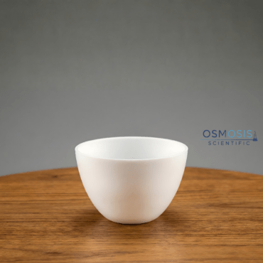 A white, bowl-shaped laboratory silica crucible resting on a wooden surface, designed for high-temperature thermal processing.