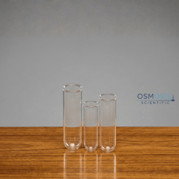 Three clear disposable glass culture tubes of varying sizes with rimmed tops, standing upright on a wooden laboratory bench.