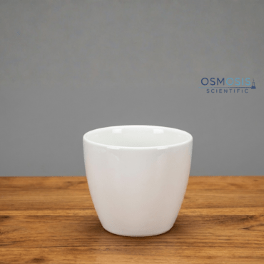 A white squat form porcelain crucible with a glazed finish and Euro design, centered on a wooden tabletop against a grey background.