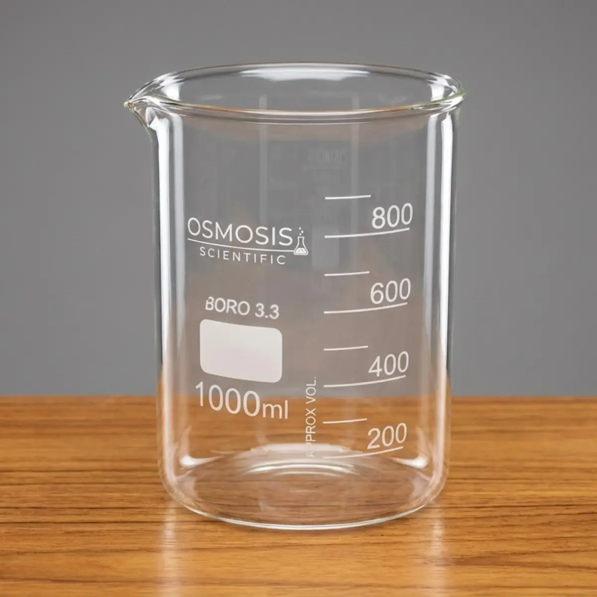 Osmosis Scientific 1000ml Tablet Disintegration Test Beaker made of Borosilicate 3.3 glass with a pouring spout and white volume graduations on a wooden surface.