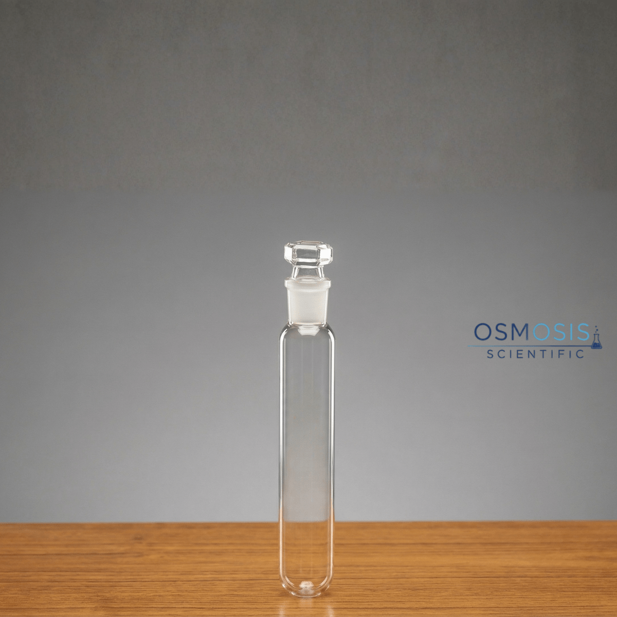A clear borosilicate glass test tube with a rounded bottom and a precision-ground interchangeable glass stopper.